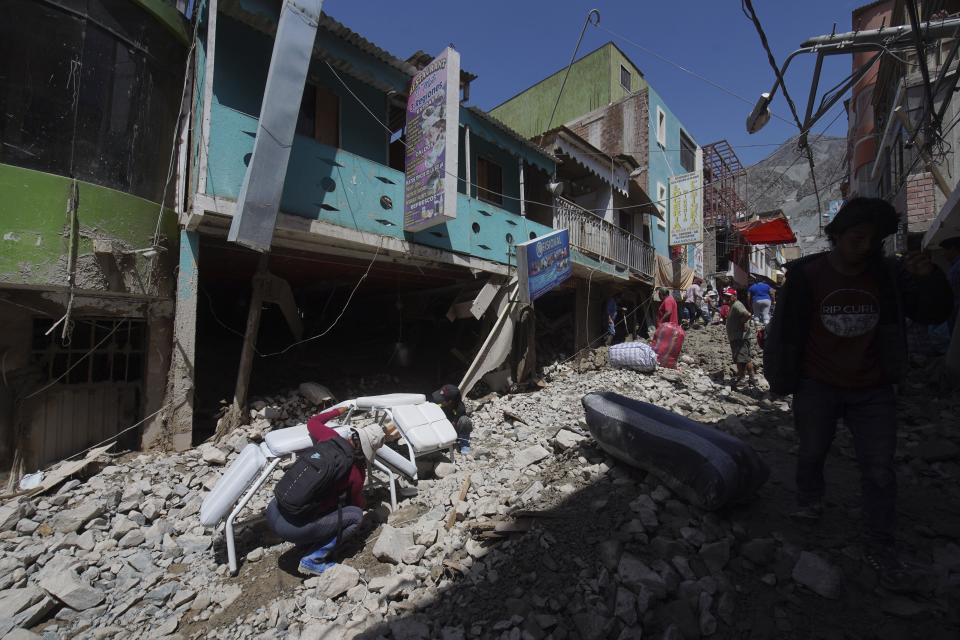 Residents recover belongings from their homes destroyed by a landslide, in Camana, Peru, Tuesday, Feb. 7, 2023. Authorities in Peru say landslides triggered by steady rains swept mud, water and rocks into several villages in the country's southern region. (AP Photo/Jose Sotomayor)