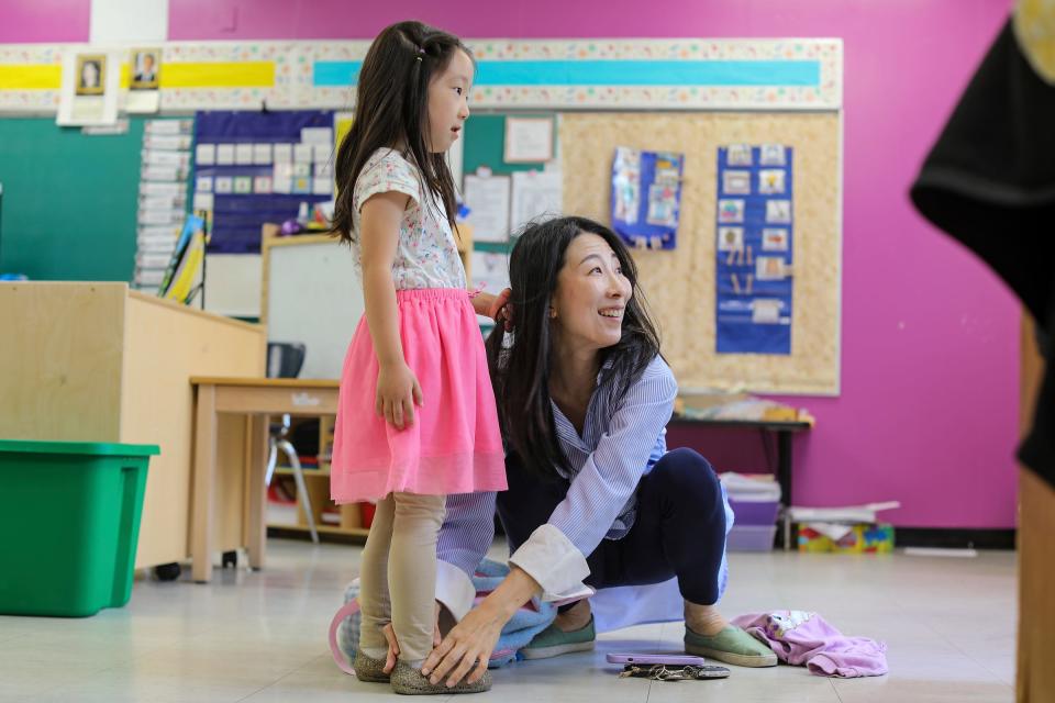 Joori Jung, 40, of Troy, helps her daughter Sia Lee, 4, put on her shoes, while Jung picks up students from her children's school for the Artlab J after-care program at Palmer Preparatory Academy in Detroit on June 7, 2023.