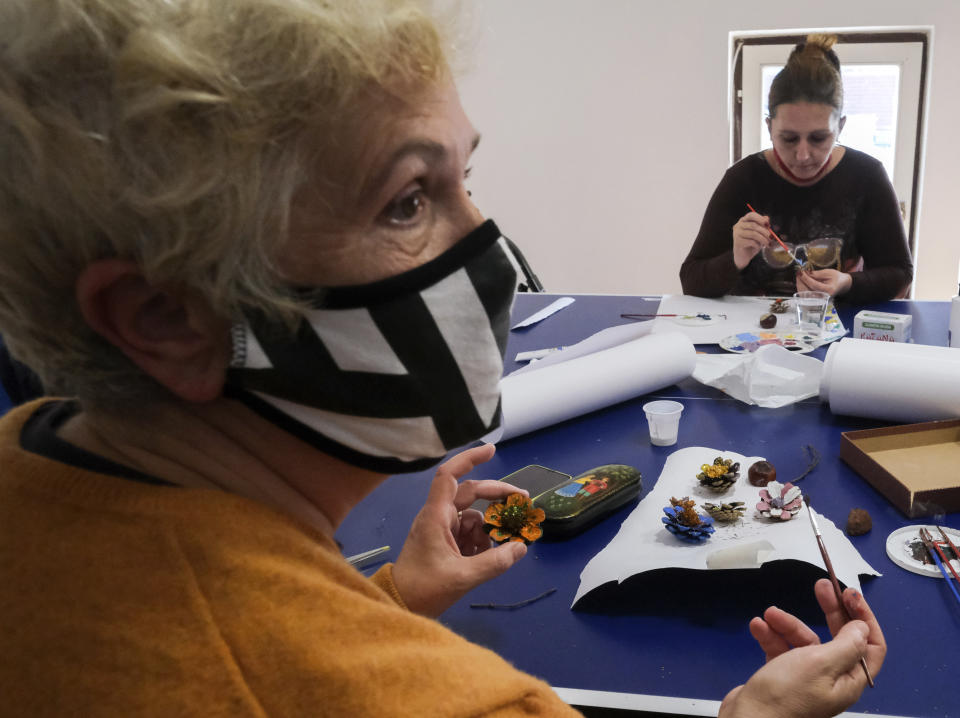 A a woman paints a pine cone during a therapy session in Sarajevo, Bosnia Monday, Oct. 26, 2020. As coronavirus cases surge in Bosnia, the pandemic is heaping new trouble on an impoverished nation that has never recovered economically or psychologically from a war in the 1990s. Bosnian health authorities estimate that nearly half of the Balkan nation’s nearly 3.5 million people have suffered some degree of trauma resulting from the war. (AP Photo/Kemal Softic)