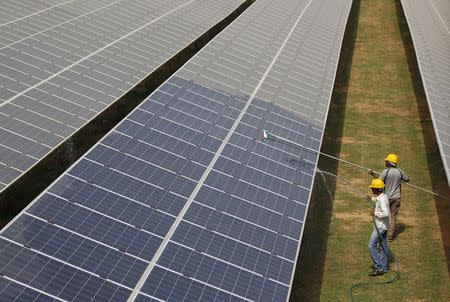 Workers clean photovoltaic panels inside a solar power plant in Gujarat, India, July 2, 2015. REUTERS/Amit Dave