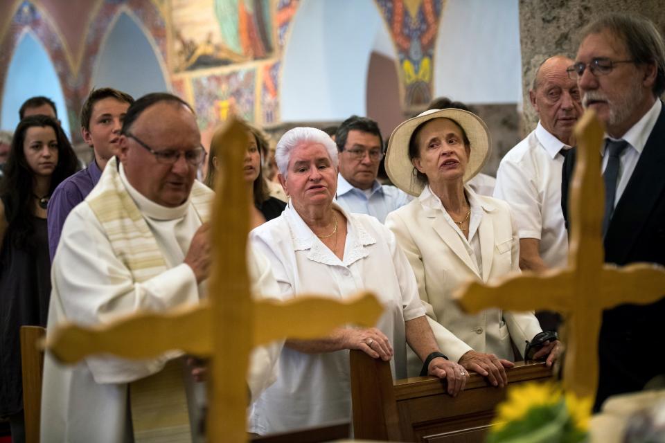 Marcelin Dumoulin's stepdaughter, Annette Dumoulin&nbsp;(C-L), is seen with one of the couple's daughters, Marcelline Udry (C-R), during the service on Saturday. (Photo: OLIVIER MAIRE via Getty Images)