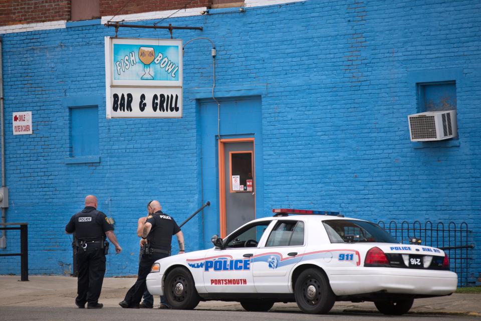 Portsmouth police talk to a man they stopped along Campbell Street in Portsmouth, Ohio. The Fish Bowl is a neighborhood bar.