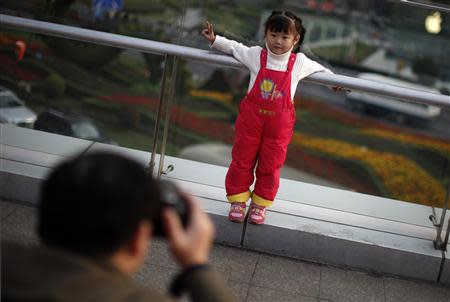 A girl poses for a photograph at a commercial area of downtown Shanghai, in this November 28, 2012 file photo. REUTERS/Carlos Barria/Files
