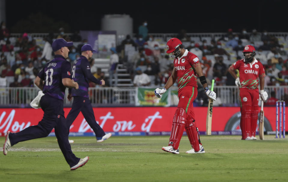 Oman's batsman Naseem Khushi, second from right, leaves the crease after being dismissed Scotland's bowler Michael Leask for 2 runs during the Cricket Twenty20 World Cup first round match between Oman and Scotland in Muscat, Oman, Thursday, Oct. 21, 2021. (AP Photo/Kamran Jebreili)