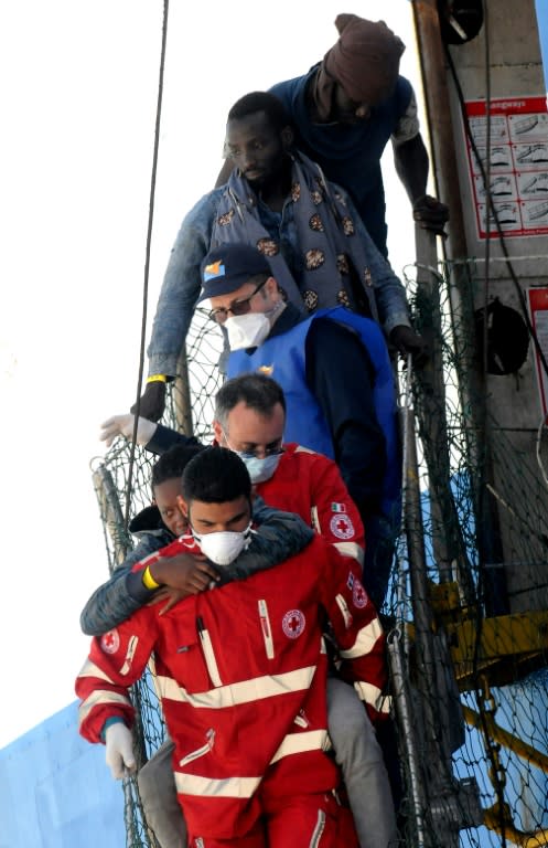 A member of the Italian Red Cross helps a rescued migrant disembark