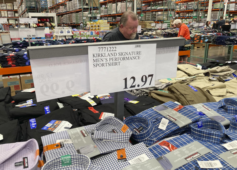 A sign displays the price for shirts as a shopper peruses the offerings at a Costco warehouse on Thursday, June 17, 2021, in Lone Tree, Colo. American consumers faced a third straight monthly surge in princes in June, the latest sign that a rapid reopening of the economy is fueling a pent-up demand for goods and services that in many cases remain in short supply. (AP Photo/David Zalubowski)