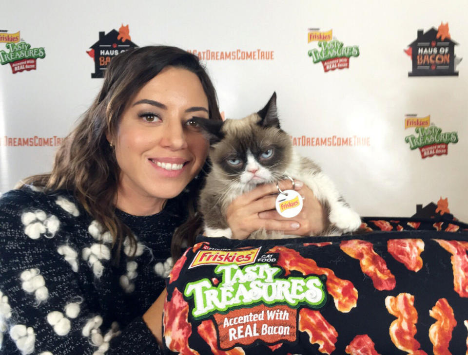 IMAGE DISTRIBUTED FOR FRISKIES - Actress Aubrey Plaza stops by Friskies Haus of Bacon to frown with Grumpy Cat in celebration of the new Tasty Treasures Accented With Real Bacon during the popular Austin-based festival on Sunday, March 15, 2015 in Austin, TX. Thanks to fan support through use of the hashtag #CatDreamsComeTrue, Friskies&amp;#174; donated 50,000 meals of the NEW Tasty Treasures&amp;#174; Accented with Real Bacon to shelter cats. (Ben Lashes/AP Images for Friskies)