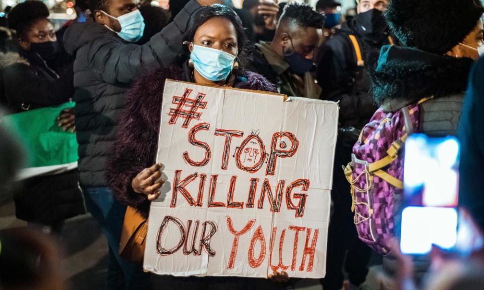 A woman holds up a sign as demonstrators at the candlelight procession remember those assaulted by Nigeria Police