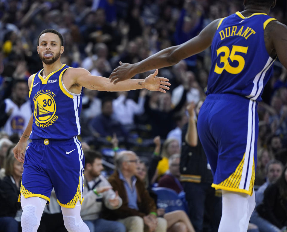 Golden State Warriors' Kevin Durant (35) high-fives Stephen Curry (30) after Curry made a 3-point shot against the Cleveland Cavaliers during the second half of an NBA basketball game Friday, April 5, 2019, in Oakland, Calif. The Warriors won 120-114. (AP Photo/Tony Avelar)