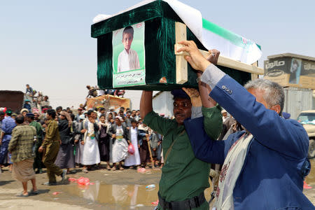 FILE PHOTO: A mourner and a policeman carry the coffin of a boy during the funeral of people, mainly children, killed in a Saudi-led coalition air strike on a bus in northern Yemen, in Saada, Yemen August 13, 2018. REUTERS/Naif Rahma/File Photo