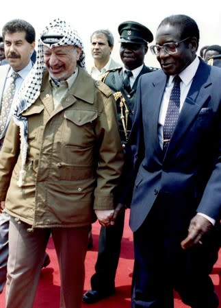 FILE PHOTO - Zimbabwe President Robert Mugabe and his Palestinian counterpart Yasser Arafat hold hands upon Arafat's arrival in the capital to attend the World Solar Summit, Zimbabwe