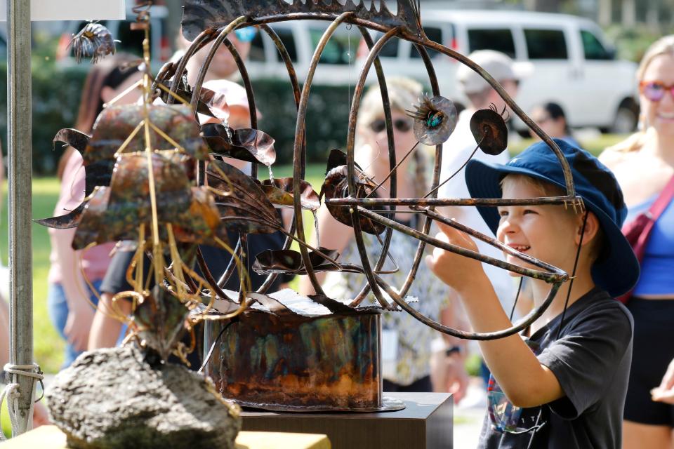 Reece Owens, 6, looks over Hog Fish, a metal kinetic sculpture by Pamela M. Chevalier of Longboat Key at the Mayfaire by-the-Lake fine art festival on Lake Morton in Lakeland on Saturday.