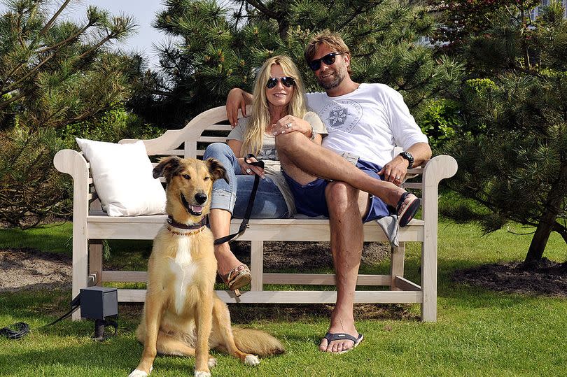 Klopp in shorts, Ulla in denim, sitting on a bench with a tan coloured dog in front