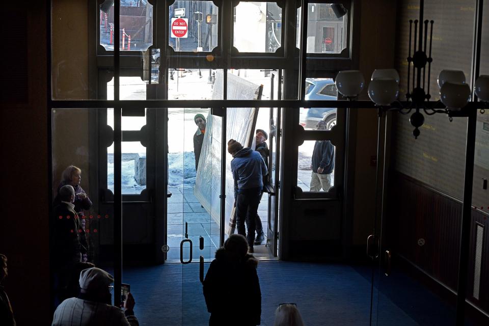 Workers manage to get the painting of 19th century Black Worcester business owners and abolitionists William Brown and Martha Brown through the front door of Mechanics Hall.