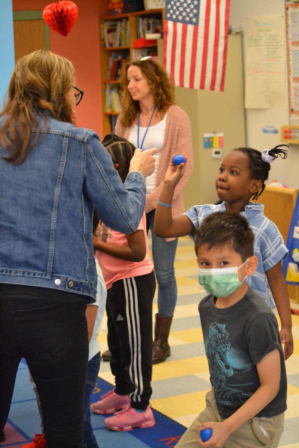 Catherine Piazza hands out small shakers to each student.