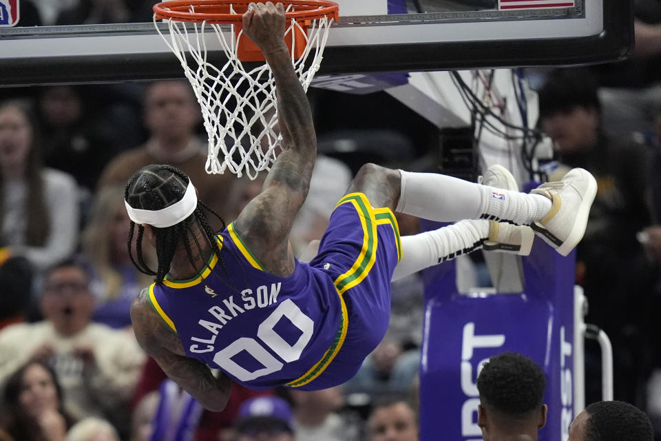 Utah Jazz guard Jordan Clarkson (00) hangs from the rim after dunking against the Charlotte Hornets during the second half of an NBA basketball game Thursday, Feb. 22, 2024, in Salt Lake City. (AP Photo/Rick Bowmer)