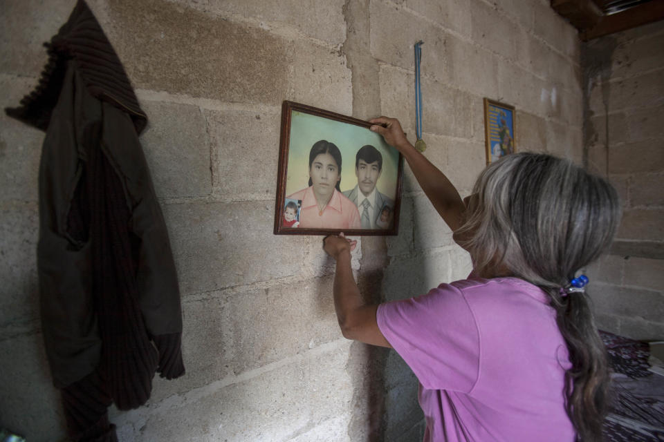 In this March 6, 2014 photo, Estercilia Gomez Arenales places on the wall a portrait of her and her late husband Jaime Callejas Tobar during an interview at her home in San Andres Itzapa, Guatemala. In November 1988 in the mountainous area of western Guatemala, 22 men who lived in the village of El Aguacate where massacred by leftists guerillas during the Guatemalan civil war. The case will be taken to court on Thursday March 13, 2014 in which more than 30 persons are expected to testify. Callejas Tobar was killed in the massacre. (AP Photo/Luis Soto)