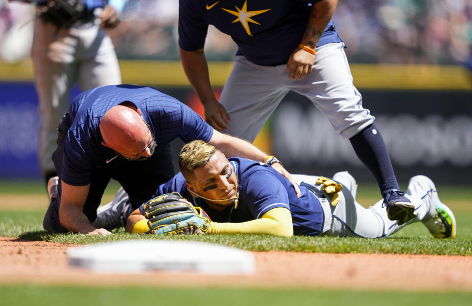 Tampa Bay Rays third baseman Isaac Paredes is checked out by a member of the Tampa Bay Rays staff after colliding with Seattle Mariners' Ty France while France was running to third base on a single by Teoscar Hernandez during the third inning of a baseball game, Sunday, July 2, 2023, in Seattle. (AP Photo/Lindsey Wasson)