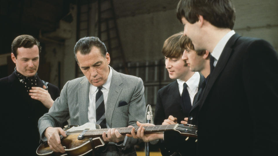 With their manager Brian Epstein (1934 - 1967) (left), members of the British Rock group the Beatles watch as American television host Ed Sullivan (1901 - 1974) tries out Paul McCartney’s Hofner violin bass during rehearsals for the ‘Ed Sullivan Show’ at the Ed Sullivan Theater, New York, February 1964.