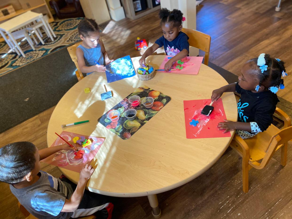 Children at Trinity House child care center paint pictures.