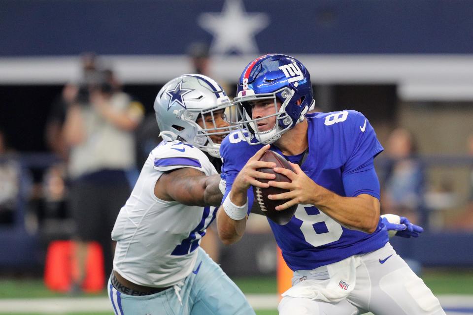 Daniel Jones #8 of the New York Giants keeps the ball and is pursued by Micah Parsons #11 of the Dallas Cowboys during the second quarter at AT&T Stadium on October 10, 2021 in Arlington, Texas.