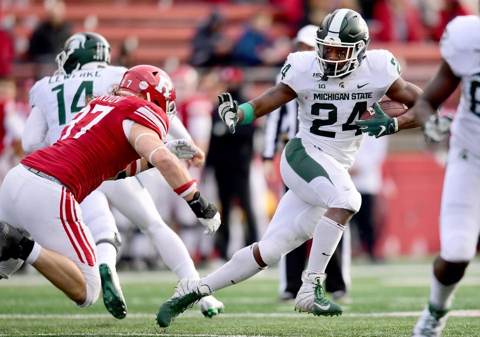 PISCATAWAY, NEW JERSEY - NOVEMBER 23: Elijah Collins #24 of the Michigan State Spartans stiff arms Mike Tverdov #97 of the Rutgers Scarlet Knights during the second half of their game at SHI Stadium on November 23, 2019 in Piscataway, New Jersey. (Photo by Emilee Chinn/Getty Images)