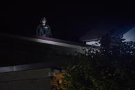 CORRECTS DAY TO FRIDAY - A Portland police officer watches from the roof of the Multnomah County Sheriff's Office while about 200 people protest on Friday, Aug. 7, 2020 in Portland, Ore. Police say demonstrators threw or launched items including rocks, frozen or hard-boiled eggs and commercial-grade fireworks toward officers early Saturday. (AP Photo/Nathan Howard)