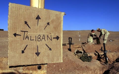 US Marines from Charlie 1/1 of the 15th MEU (Marine Expeditionary Unit) fill sand bags around their light mortar position on the front lines of the US Marine Corps base in southern Afghanistan, December 1, 2001.  - Credit: Jim Hollander/ REUTERS