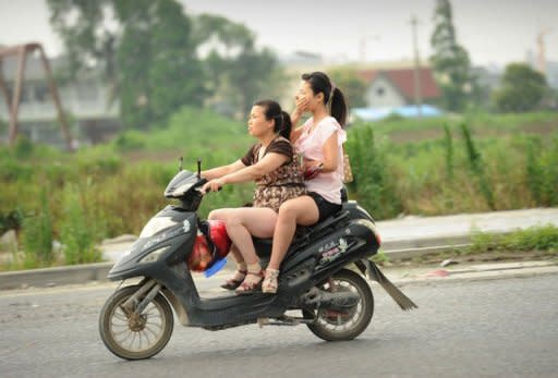 A woman on the back of a motorcycle covers her nose against the stench rising from a garbage dump in the Songjiang district of Shanghai. Hundreds took to the streets in late May and dozens again in early June to oppose the landfill and a planned garbage incinerator, which officials had proposed to solve the festering problem