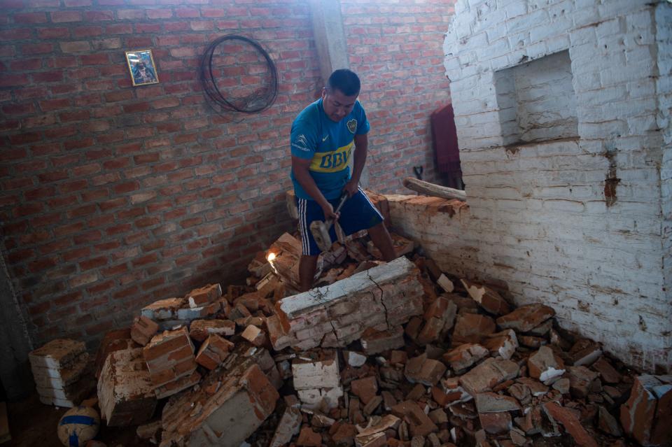 A man fixes his house, damaged by the floods during the El Niño Costero phenomenon, at Pedregal district in Piura, northern Peru on October 17, 2021. - Thousands of climate migrants who lost their homes and livelihoods due to the El Nino Costero phenomenon five years ago, live in precarious camps in the desert in northern Peru. (Photo by Ernesto BENAVIDES / AFP) (Photo by ERNESTO BENAVIDES/AFP via Getty Images)