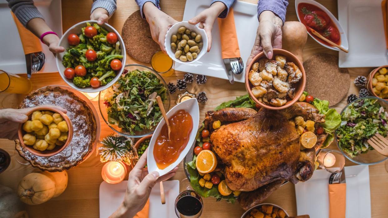 high angle view of unrecognizable people passing side dishes during thanksgiving dinner at dining table