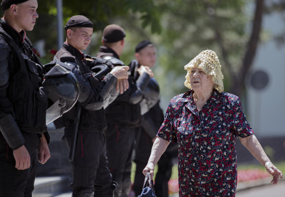 An elderly woman walks by a line of riot policemen standing outside the government headquarters in Chisinau, Moldova, Wednesday, June 12, 2019. Moldova's police chief on Wednesday dismissed six officers who publicly backed a rival government, reflecting a continuing power struggle that has heightened political tensions in the impoverished ex-Soviet nation.(AP Photo/Roveliu Buga)