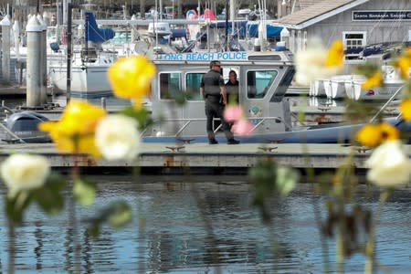 Long Beach police are viewed through a makeshift memorial near Truth Aquatics as the search continues for those missing in a pre-dawn fire that sank a commercial diving boat near Santa Barbara, California