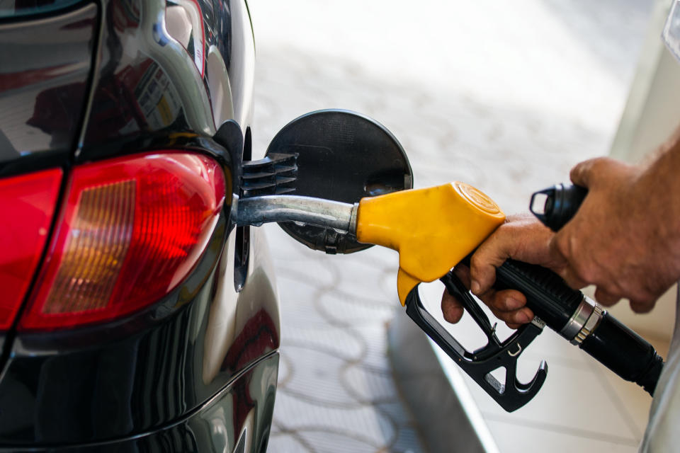 Pumping gas at gas pump. Closeup of man pumping gasoline fuel in car at gas station. Man's hand refueling car at gas station