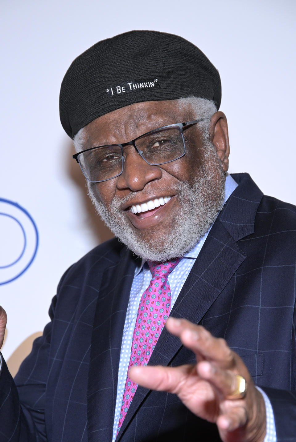 George Wallace in a beret and glasses at an event wearing a pinstripe suit, patterned tie