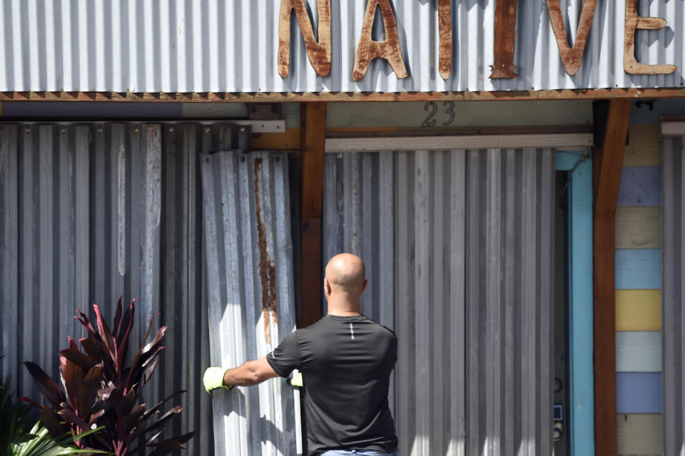 A worker affixes corrugated metal to the front of a business along the main drag in Folly Beach, S.C., on Tuesday, Sept. 3, 2019. Businesses and residents throughout the Charleston area continued to prepare structures for the arrival of Hurricane Dorian as the storm battered the Bahamas with life-threatening storm surge. (AP Photo/Meg Kinnard)