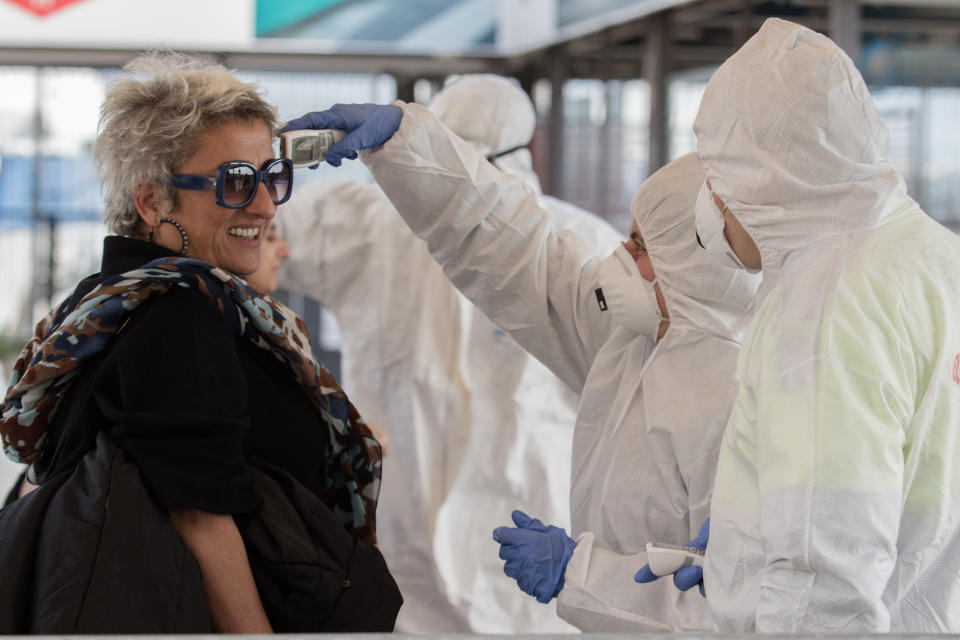 An epidemic prevention staff member checks a person's body temperature at the port of Naples.