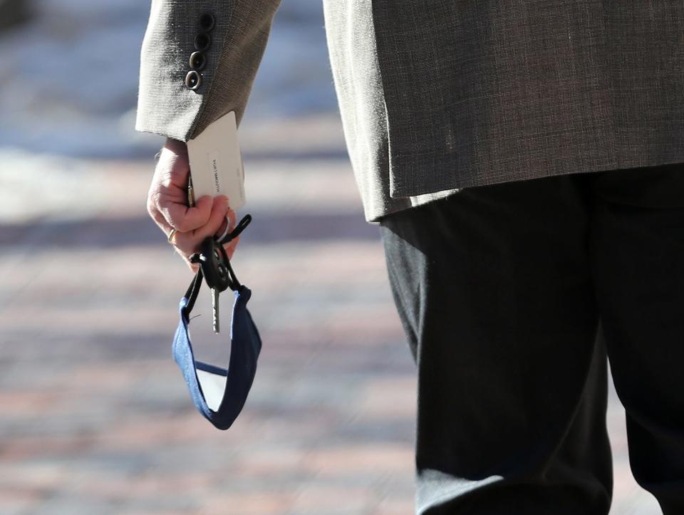 A man carries his keys and face mask as he walks in Market Square in Portsmouth Monday, Jan. 10, 2022.