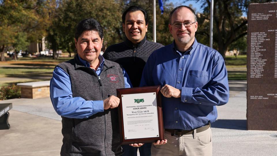 Posing with a plaque earned by West Texas A&M University for Professional Grounds Management Society’s Green Star Awards are, from left, Stan Pena, WT assistant vice president for facilities; Carlo Vazquez, SSC unit director; and Brandon Hayley SSC senior project manager.