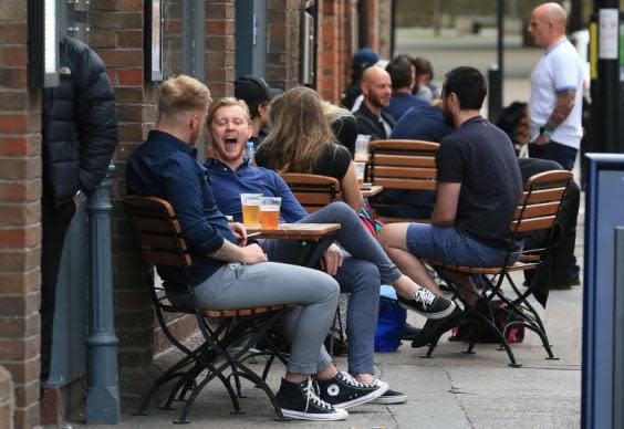 Customers sit with drinks outside a re-opened pub in Newcastle, on 4 July (AFP)