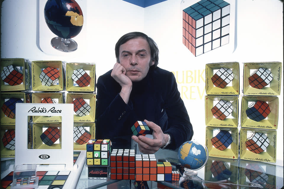 a picture of erno rubik with rubik's cubes around him
