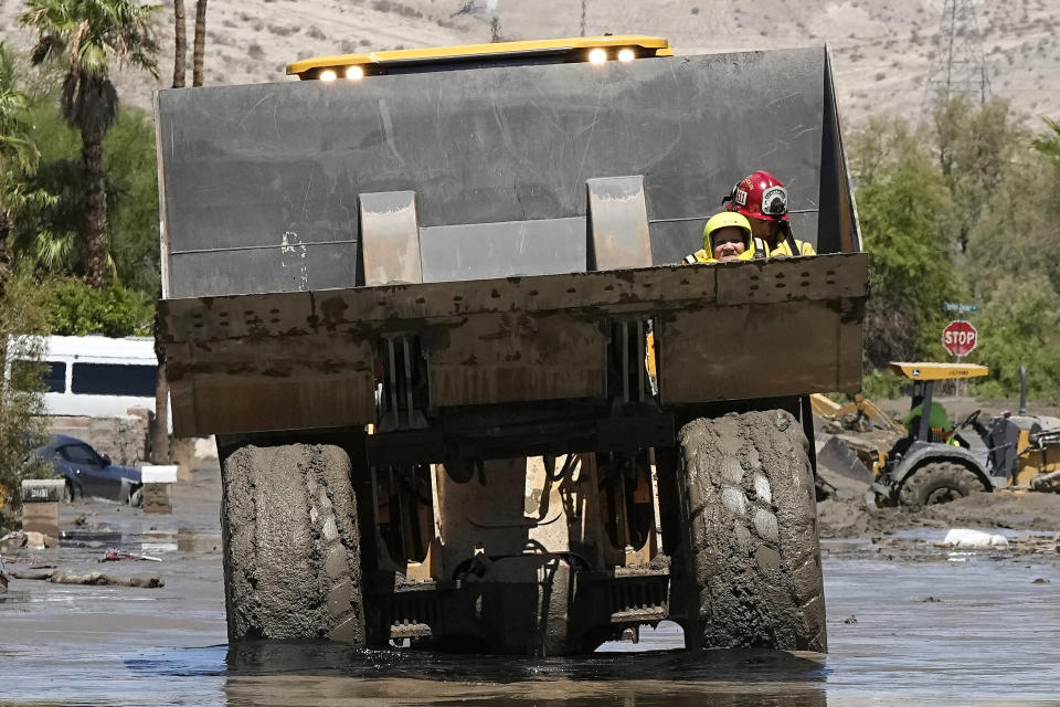 Firefighters use a skip loader to rescue a person from an assisted living center after the street was flooded with mud Monday, Aug. 21, 2023, in Cathedral City, Calif. Forecasters said Tropical Storm Hilary was the first tropical storm to hit Southern California in 84 years, bringing the potential for flash floods, mudslides, isolated tornadoes, high winds and power outages. (AP Photo/Mark J. Terrill)