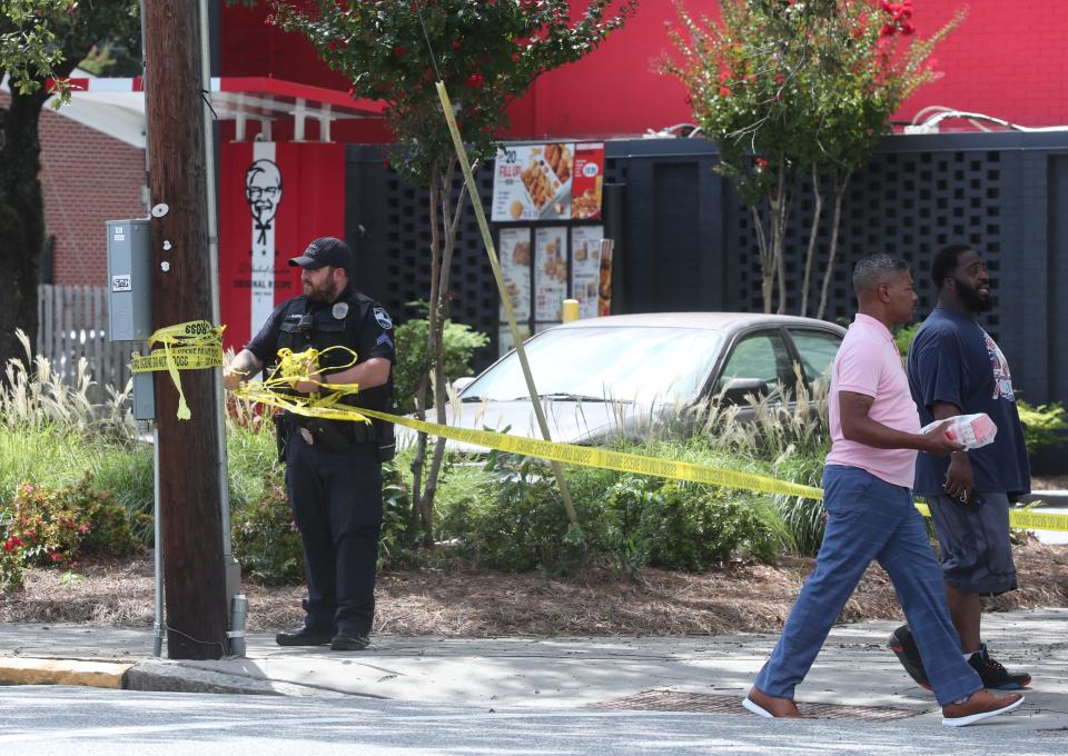 A Savannah Police officer removes crime scene tape at the KFC on West Gwinnett Street following shooting on Thursday, August 10, 2023.