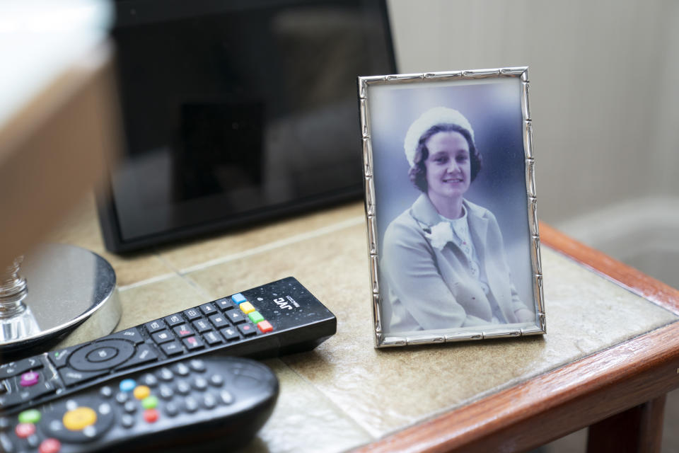 A photo of the late Muriel Bonner taken in Belgium in 1979, stands on a table in the home of her husband Gordon Bonner, in Leeds, England Saturday Jan. 23, 2021. For nine months, Gordon Bonner has been in the "hinterlands of despair and desolation" after losing Muriel, his wife of 63 years, to the coronavirus pandemic that has now taken the lives of more than 100,000 people in the United Kingdom. ( AP Photo/Jon Super)