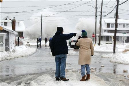 Two people watch the waves crash in the distance during a winter nor'easter snow storm in Scituate, Massachusetts January 3, 2014. REUTERS/Dominick Reuter