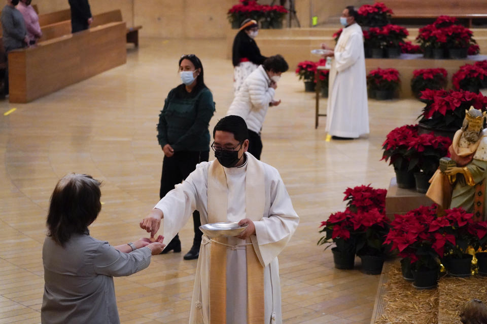 Worshipers receive communion during a Christmas Eve Mass inside the Cathedral of Our Lady of the Angels Thursday, Dec 24, 2020, in Los Angeles. California became the first state to record 2 million confirmed coronavirus cases, reaching the milestone on Christmas Eve as nearly the entire state was under a strict stay-at-home order and hospitals were flooded with the largest crush of cases since the pandemic began. (AP Photo/Ashley Landis)