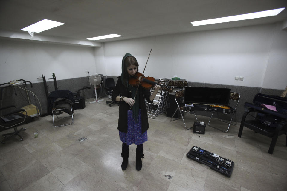 In this picture taken on Friday, Feb. 1, 2013, female Iranian violinist Nastaran Ghaffari practices for her band called "Accolade" in a basement of a house in Tehran, Iran. Heavy metal guitarists jamming in basements. Headphone-wearing disc jockeys mixing beats. Its an underground music scene that is flourishing in Iran, despite government restrictions. (AP Photo/Vahid Salemi)