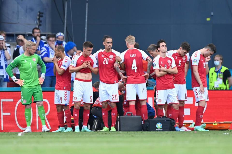 Denmark players protect Christian Eriksen as he receives live-saving treatment during their match against Finland on 12 June