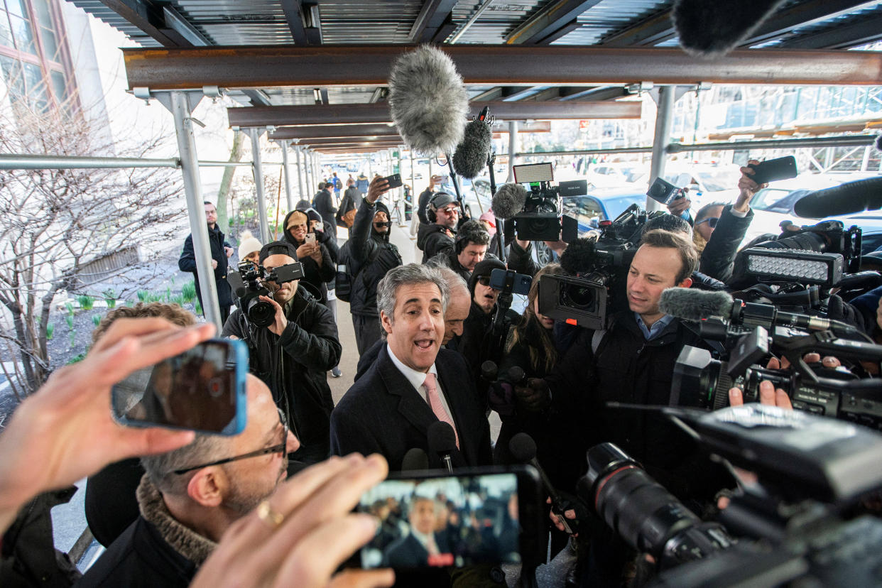 Michael Cohen speaks as he is surrounded by reporters with microphones and cameras.