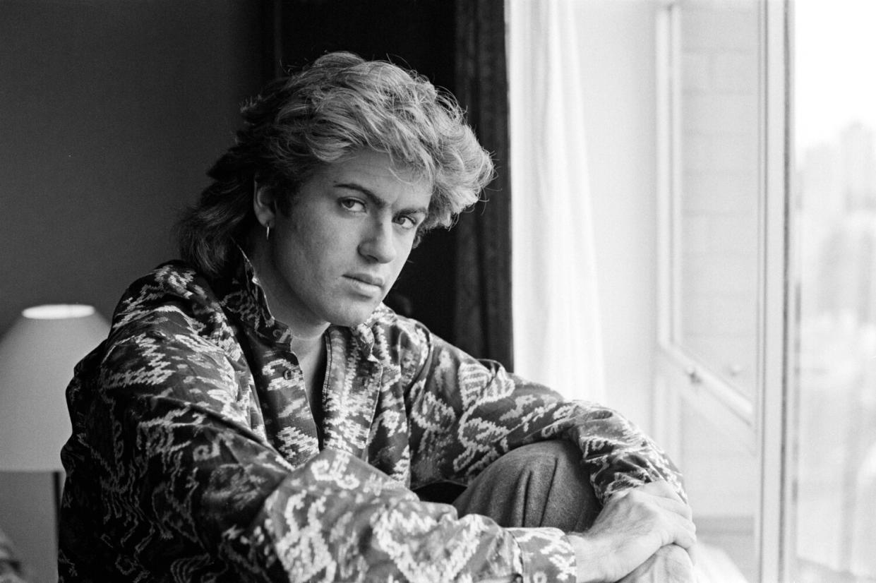 A man sits in front of a window and poses for a black and white portrait